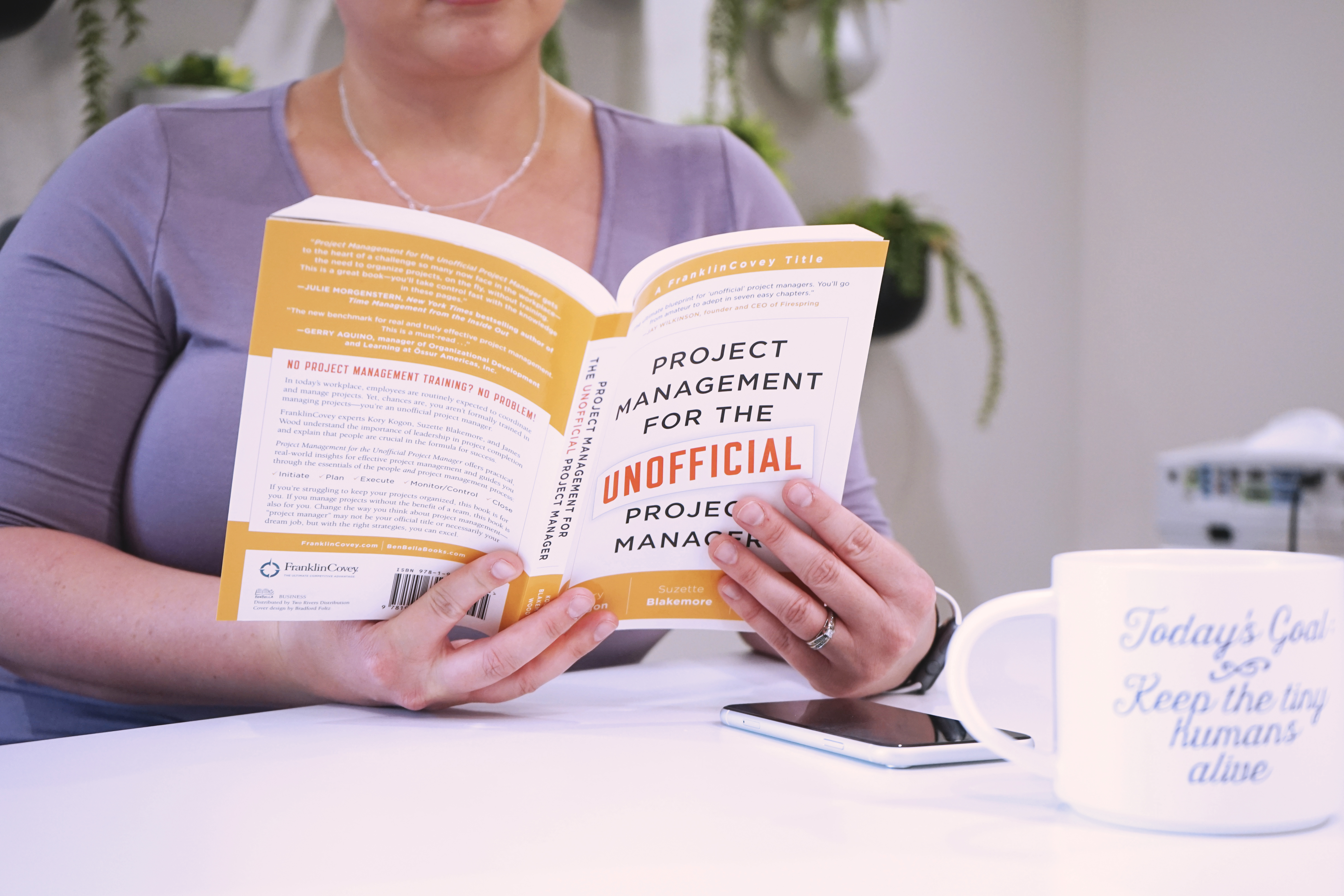A 9 to 5 Office team member reading Project Management for the Unofficial Project Manager.
